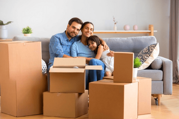 Une famille assise au milieu des cartons de déménagement